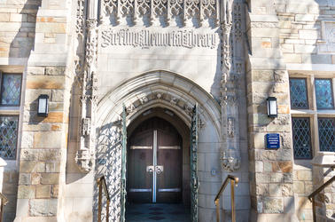 Exterior of 301 York Street with a wooden door, open metal gate, and stone facade.